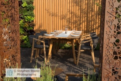 Photographer: Stephen Studd - The Urban Flow Garden: laser cut corten steel pillars, edible vertical wall planted with lettuce, herbs and nasturtium, brick paved patio with table and chairs, wood panel garden wall - Designer: Tony Woods - Sponsor: Thames Water